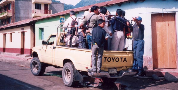 Photo of Guatemalen people riding in the back of a pickup truck